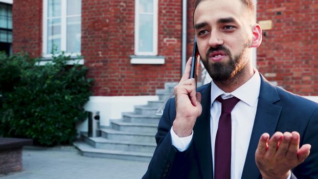 Man in business suit talking on the phone, outdoor in the city. Slow motion footage