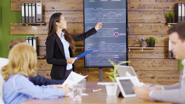 Young business woman in suit having a successful presentation in front of her management team.