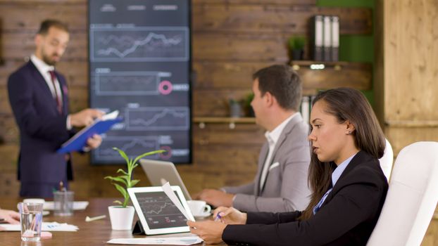 Female coworker analysing charts in the conference room. Corporate meeting.