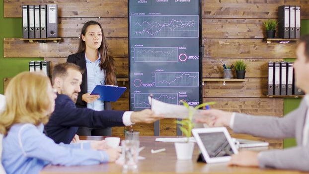Young business woman in suit having a successful presentation in front of her management team.