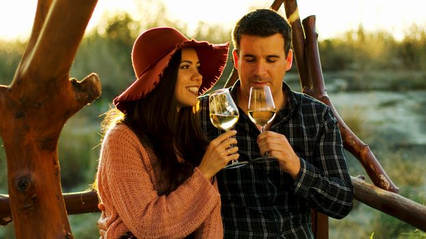 Couple having a romantic moment, tasting some white wine in beautiful sun flares.