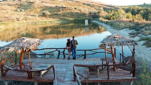 Couple on a pontoon bridge in a vacation in rural area with a lake, drone aerial footage
