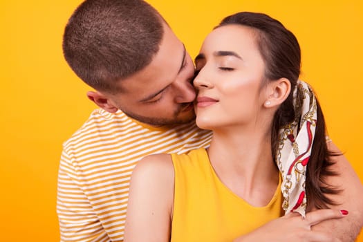 Handsome boyfriend kissing his beautiful girlfriend from behind on her cheek. Relationship goals.