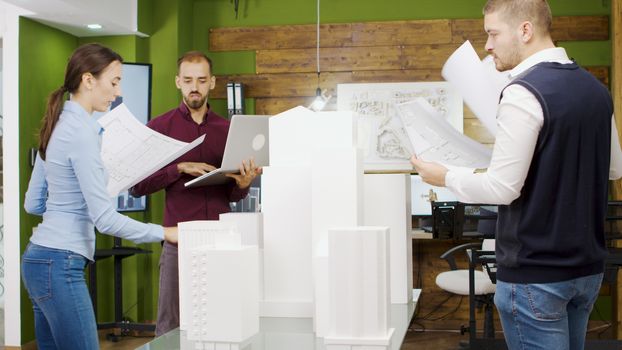 Team of architect working on a building project with building models and holding blue print.
