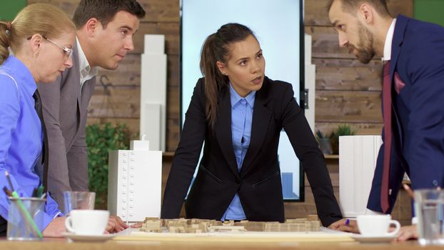 Team of developers talking about new town project in the meeting room. Mini town