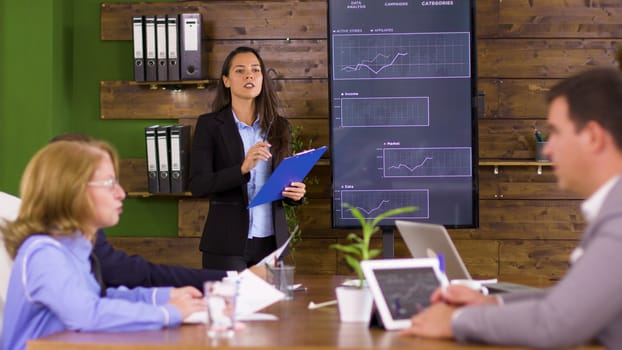 Successful businessman reading charts on his tablet. Businessman with his team in the conference room.