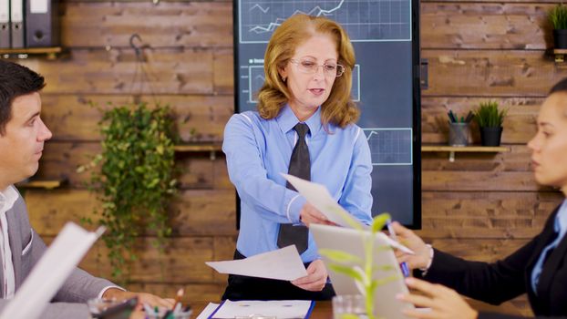 Confident female director giving charts to new investors. Breaking annual revenue.