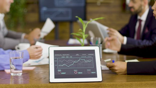 Tablet PC with graphs in a conference room. Team brainstorm.
