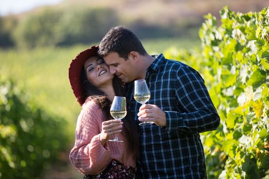 Couple together with a glass of wine in vineyard. Couple having a sweet moment in a vineyard.