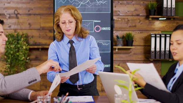 Confident female director giving charts to new investors. Breaking annual revenue.