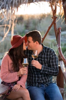 Couple in love kissing sitting on a bench by the edge of a lake in the middle of a big vineyard.