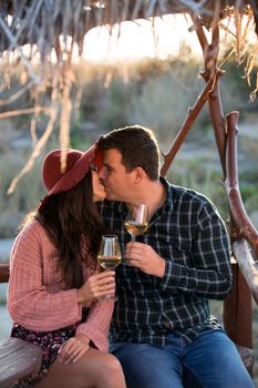 Couple kissing on a wooden ponton by the edge of a lake in the middle of a big vineyard.