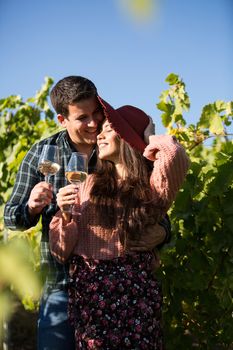 Cheerful young wife with her husband enjoying their time together in a vineyard. Couple in love with good wine.