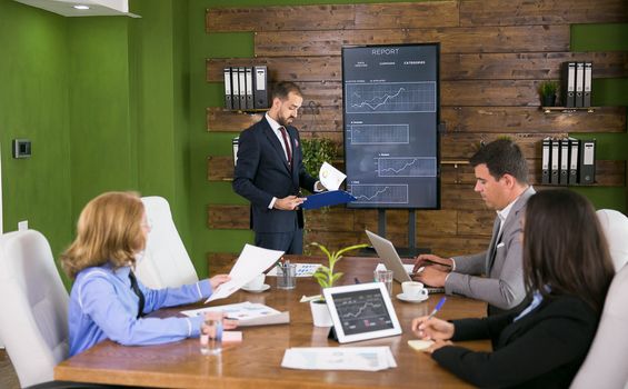 Businessman in suit checking his note on clipboard in conference room. Entrepreneurs meeting.