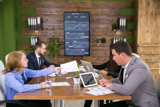 Team of entrepreneurs having a meeting in the conference room with charts on tv screen.