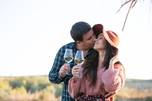 Husband kissing his wife cheek by the egde of a lake on a wooden ponton in the middle of a big vineyard.