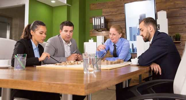 Female real estate developer in a meeting with her team of architects in conference room. Mini town. Building project.