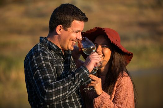 Man and woman with glasses of wine in his hands on the sunset in a vineyard.