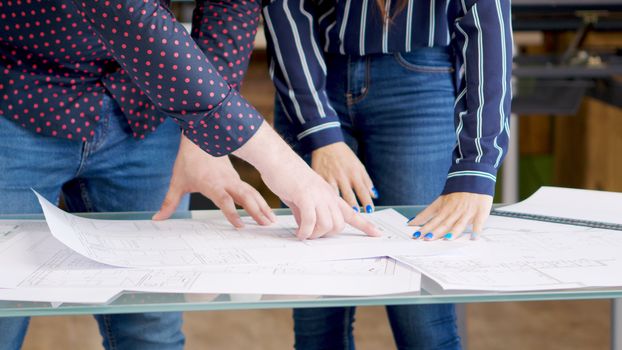 Male architect pointing at something on blueprints near his female colleague
