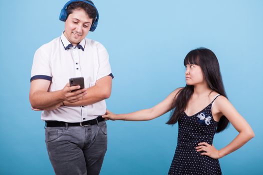 Upset asian girlfriend on her boyfriend for ingnoring her while using his phone. Interracial couple.