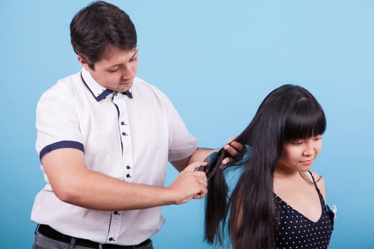 Caucasian husband brushing hair of his asian wife in studio. Interracial couple