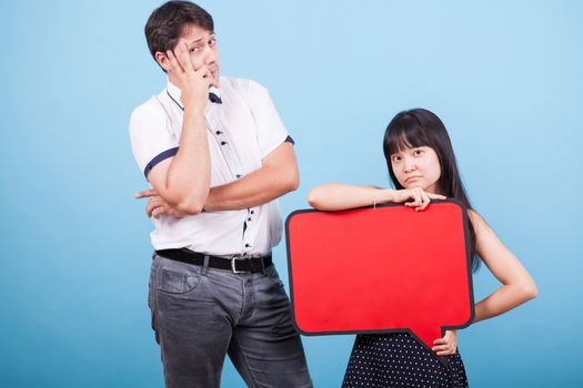 Serious interracial couple with blank sign in studio. Asian girl holding empty bubble thought.
