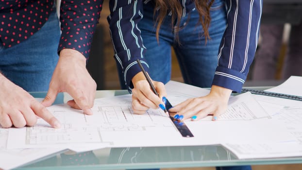 Male and female architect looking over blueprints in modern office