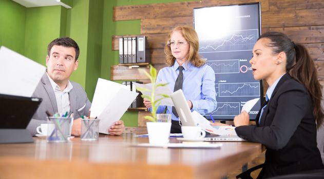 Business woman making a presentation in a conference room with charts on tv screen,