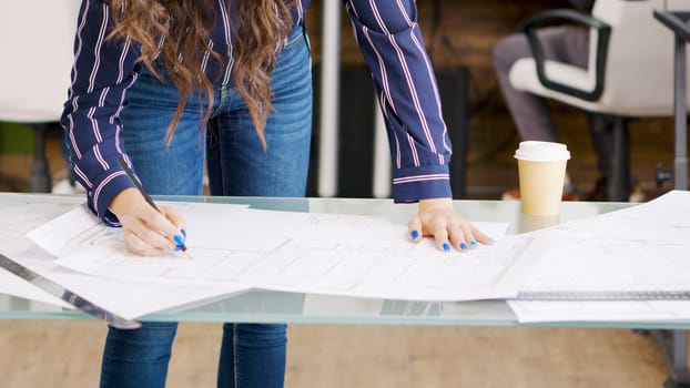 Close up shot of creative designer working on blue prints in modern office
