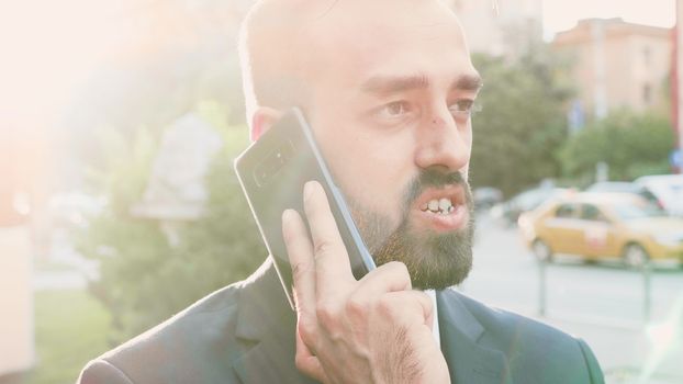 Portrait of handsome businessman talking on the phone while lens flares are hitting the screen. Slow motion close up