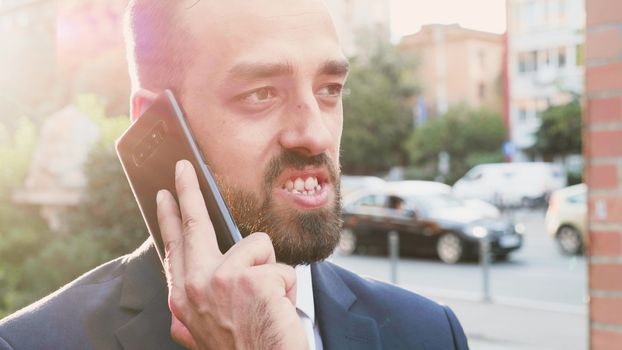 Portrait of business person talking on the phone with the sun behind him in the city creating beautiful lens flares. Slow motion shot