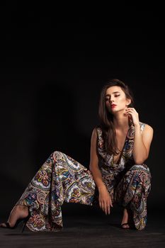 Stylish fashion model posing in studio wearing colorful pants over black background. Brunette fashion model.