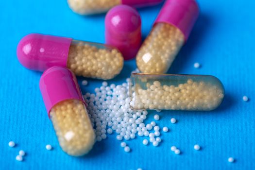 Close up with open capsules and the substance in them is shed next to them. Macro and blue background