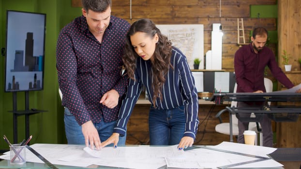 Team of architects in modern office looking at blueprints