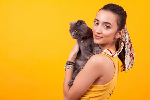 Portrait of beautiful girl holding adorable cat and looking at the camera.