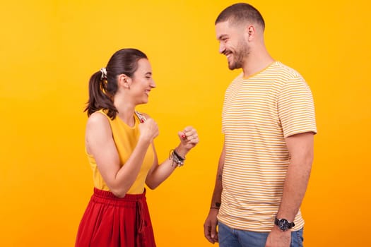 Smiling and beautiful girlfriend keeping her fists up in front of her boyfriend. Cheerful couple.