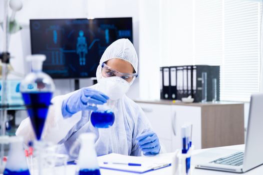 Chemist follows a reaction in the tube from which white smoke comes out.