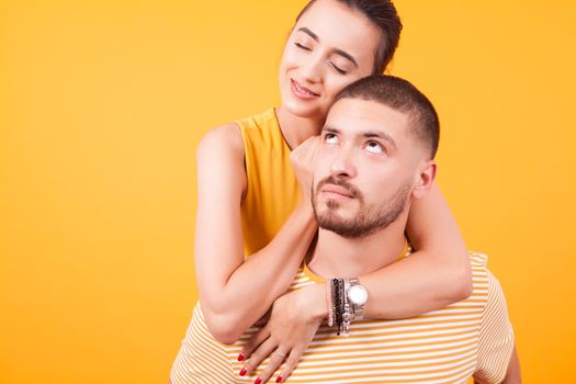 Girlfriend showing love to her boyfriend while he's peggybacking her. Happy young couple.