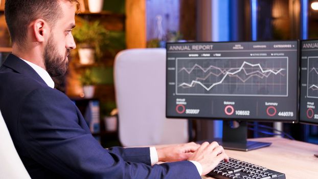 Close Up with businessman patching something on keyboard. Graphics on the monitor