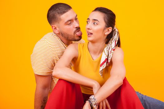 Boyfriend sticking tongue out on his beautiful girlfriend. Cheerful couple.