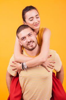 Beautiful girlfriend with eyes closed while boyfriend ofer a piggyback. Boyfriend carrying his girlfriend.