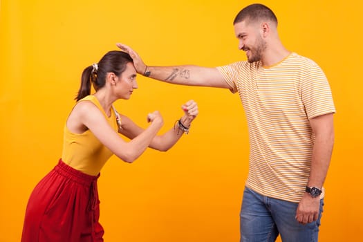 Cute couple having fun in a studio over yellow background
