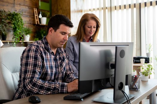 Man and female manager talking in modern business office. Big windows in the background