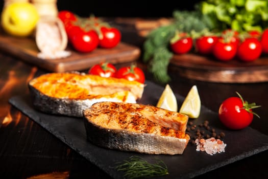 Grilled salmon rings placed on a stone platter. Salt and tomatoes in the background