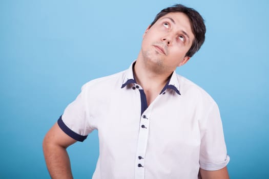 Thoughtful caucasian young man in white shirt looking up. Thinking about a solution.