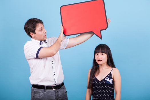 Shocked asian girlfriend while boyfriend holding empty sign over her head. Interracial couple.