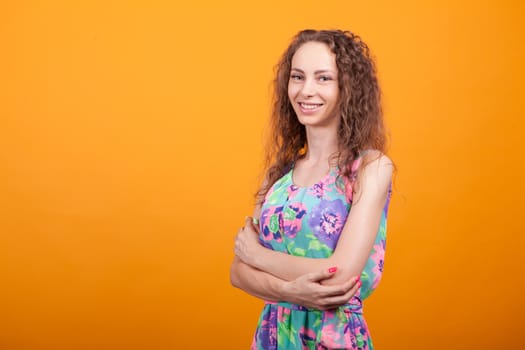Side view studio shot of cheerful woman with hands crossed and big natural smile.