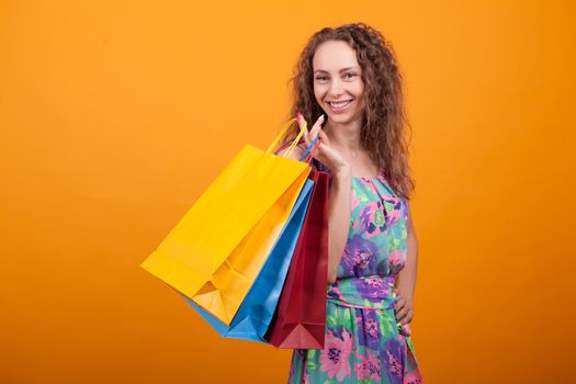 Fancy woman smiling and holding colorful shopping bags. Joyful and stylish woman.