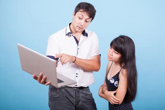 Caucasian male pointing at laptop and consulting with his asian wife. Interracial couple.