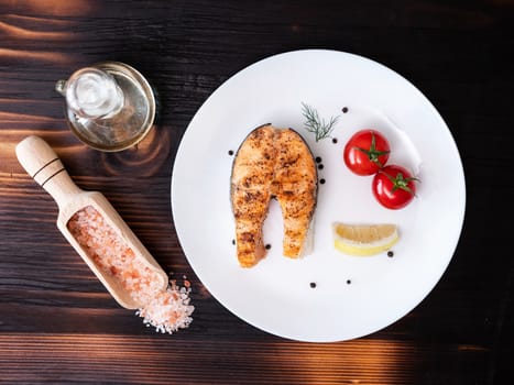Top view with a piece of salmon arranged in a white plate and pressed with salt and pepper